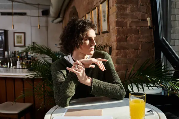 A handsome young man relaxes at a cafe, quietly savoring his time while sipping a refreshing drink. — Stock Photo