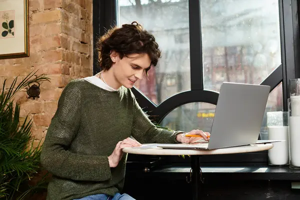 Focused young man sits at a cafe table, typing on his laptop and enjoying a cozy atmosphere. — Stock Photo