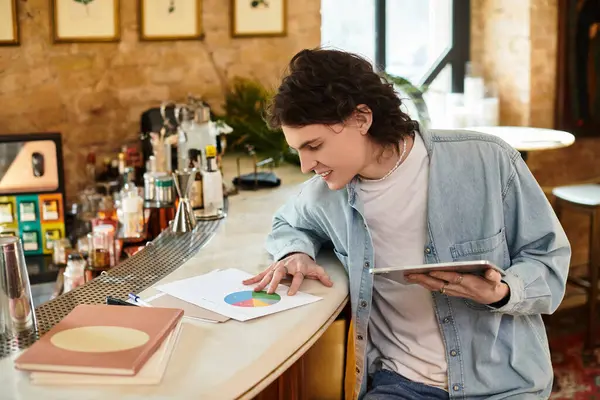 Un giovane uomo impegnato in un compito analitico in un accogliente caffè, rivedendo grafici e grafici vibranti. — Foto stock