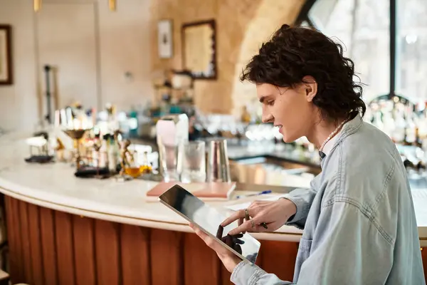 En un acogedor café, un joven guapo se involucra con su tableta, saboreando un momento de ocio. - foto de stock