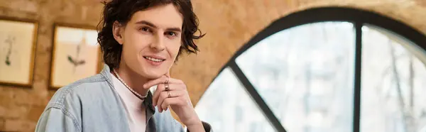 Young handsome guy seated in a stylish cafe, smiling and relaxing while savoring the moment. — Stock Photo