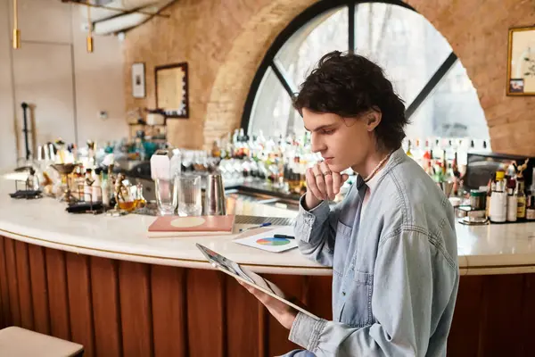 A stylish young man engrossed in thoughts while exploring his interests at a vibrant cafe. — Stock Photo