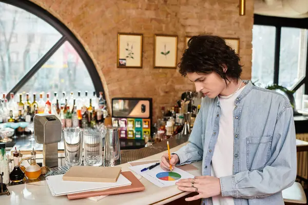 In a stylish cafe, a young man focuses on his project, sketching ideas and notes while relaxing. — Stock Photo