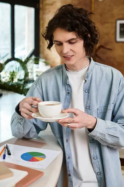 A young handsome man sits comfortably in a quaint cafe, savoring his warm coffee. — Stock Photo