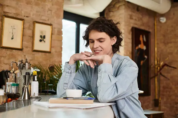 A young handsome guy relaxes at a cafe, savoring a warm drink while deep in thought. — Stock Photo