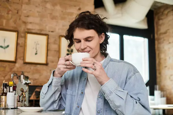 A young handsome man savors his coffee while sitting in a stylish cafe with a charming atmosphere. — Stock Photo