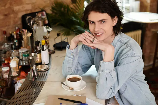 A handsome young man relaxes at a cafe, sipping coffee in a charming setting. — Stock Photo