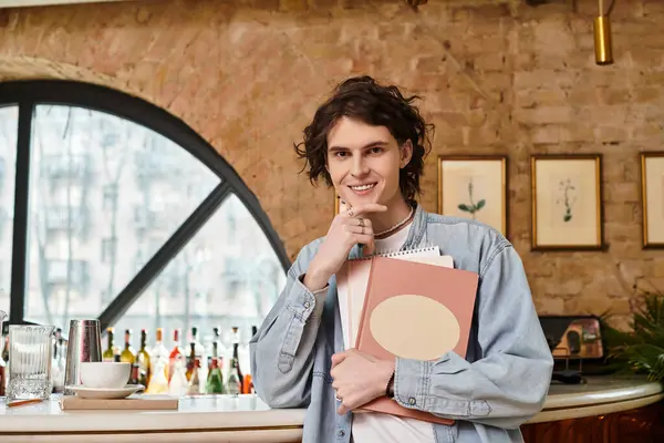 A young, handsome guy relaxes at a cafe, drawing in his sketchbook with a cheerful vibe. — Stock Photo