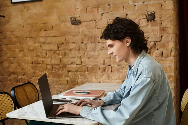 A young man focuses on his laptop, surrounded by a warm atmosphere at a cafe while relaxing. — Stock Photo