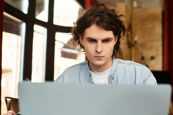 A young man immersed in his laptop at a charming cafe, enjoying a relaxing afternoon. — Stock Photo
