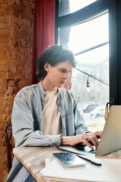A young man at a sunny cafe table works on his laptop, enjoying a peaceful afternoon. — Stock Photo