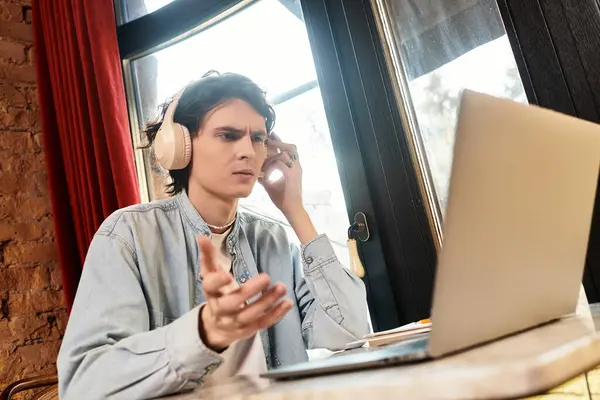 Bel ragazzo si siede in un caffè, indossa le cuffie, profondamente impegnato in una discussione virtuale. — Foto stock