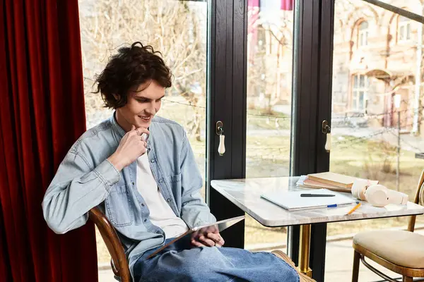 Un beau jeune homme se détend dans un café tout en s'engageant avec sa tablette, profitant de l'ambiance. — Photo de stock