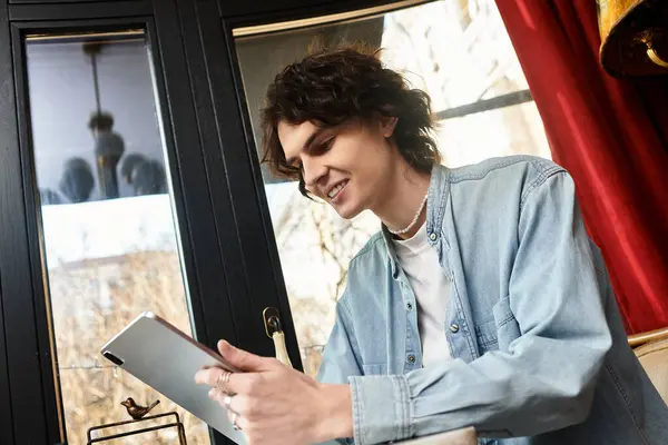 A young handsome guy relaxes in a cafe, enjoying his time as he engages with his tablet. — Stock Photo