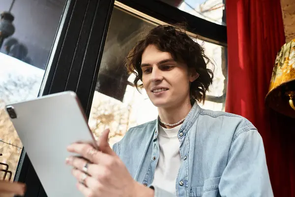 Jovem confiante se envolve com um tablet, desfrutando do ambiente quente de um café animado. — Fotografia de Stock