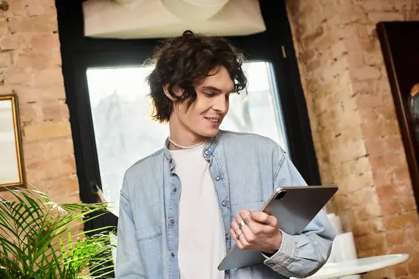 A young, attractive man interacts with a tablet in a cozy cafe, radiating confidence and leisure. — Stock Photo
