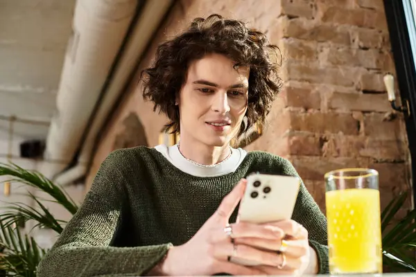 Handsome young guy relaxes at a cafe, engaged with his smartphone and enjoying a refreshing drink. — Stock Photo