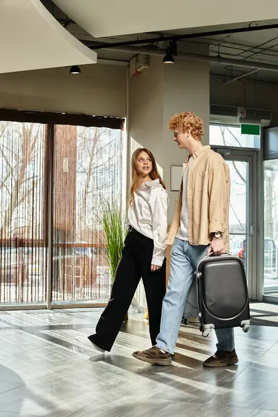 Una joven pareja pasea por un elegante vestíbulo del hotel, compartiendo sonrisas y disfrutando del tiempo juntos. - foto de stock
