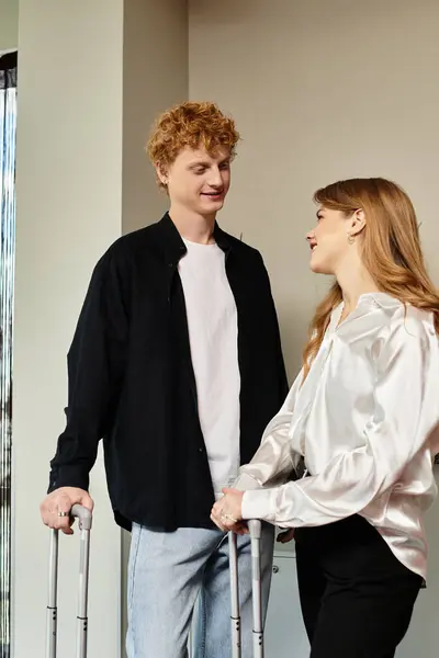 A young couple shares affectionate glances while holding luggage in a chic hotel setting. — Stock Photo