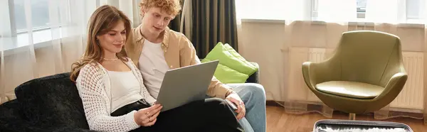 A young couple cuddles on a couch, sharing smiles while exploring a tablet in a cozy hotel room. — Stock Photo