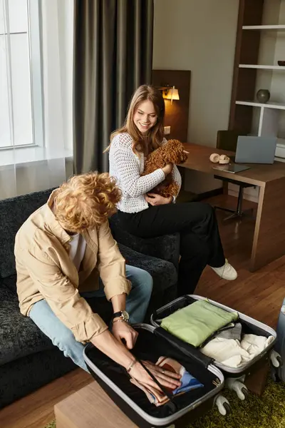 In a warm hotel room, a young couple shares laughter as they pack their belongings for adventure. — Stock Photo