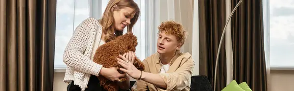 In a modern hotel, a young couple lovingly interacts with their adorable pet, radiating happiness. — Stock Photo