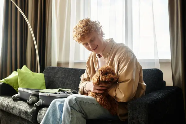 A young man relaxes in hotel, enjoying time together with his small dog. — Stock Photo