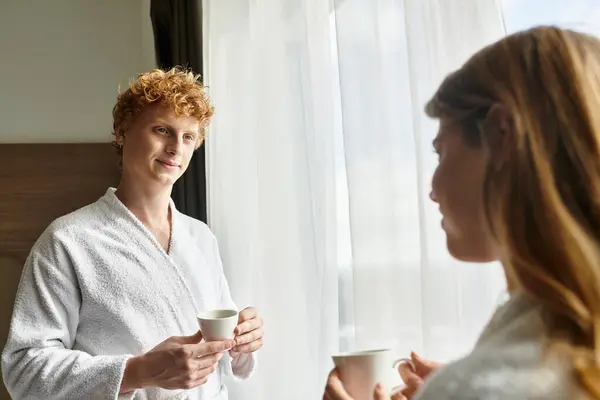 A young couple shares a tender moment while enjoying coffee together in their hotel room. — Stock Photo