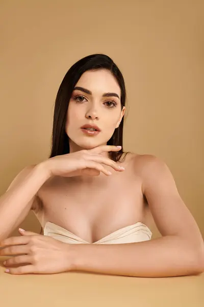 A young woman presents her flawless, glowy skin while relaxing in a calming studio atmosphere. — Stock Photo