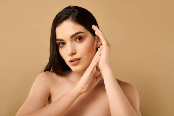 Una joven mujer muestra su piel brillante con confianza en un ambiente tranquilo estudio. - foto de stock