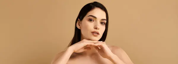 A young woman with radiant skin poses gracefully in a studio setting, exuding beauty, banner — Stock Photo