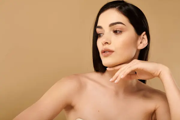 Una joven confiada muestra su piel radiante en un estudio minimalista. - foto de stock