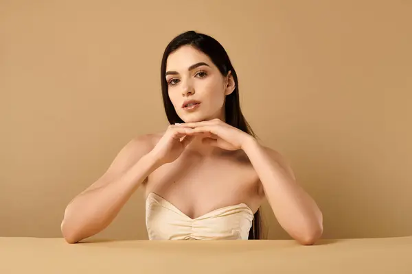 Jeune femme présente une peau impeccable avec une expression sereine dans un studio aux tons chauds. — Photo de stock