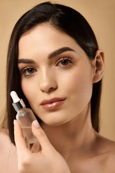 Young woman with radiant skin holds a serum bottle, highlighting her beauty routine in a studio. — Stock Photo