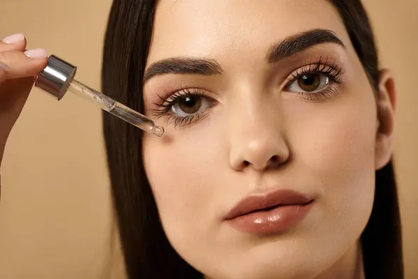Young woman applies serum to her flawless skin, highlighting the essence of beauty and self-care. — Stock Photo