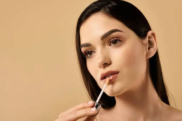 Glowing young woman enhances her beauty routine in a serene studio environment. — Stock Photo