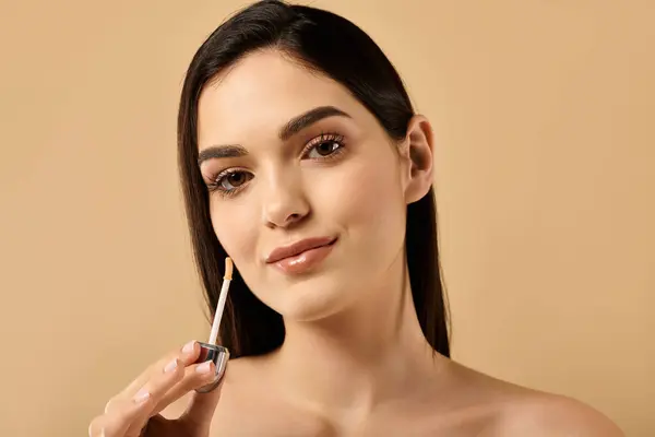 Young woman showcases her radiant skin while applying skincare product in a studio. — Stock Photo
