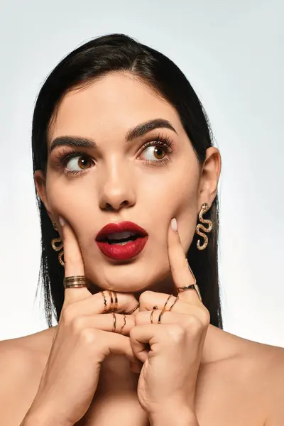 A beautiful young woman shows off her vibrant red lips and stylish jewelry while posing elegantly. — Stock Photo
