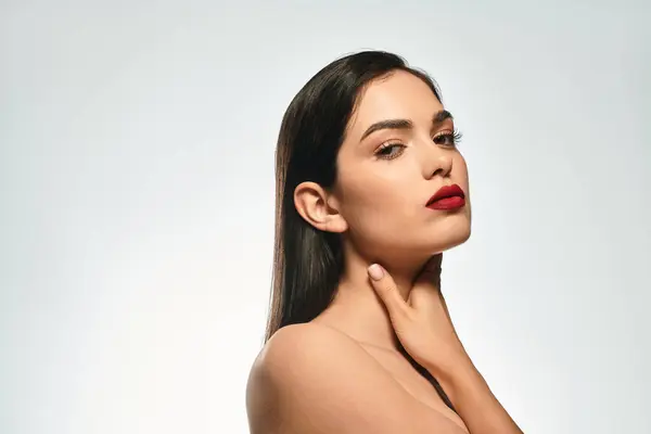 A beautiful young woman showcases her captivating red lips and flawless makeup with elegance. — Stock Photo
