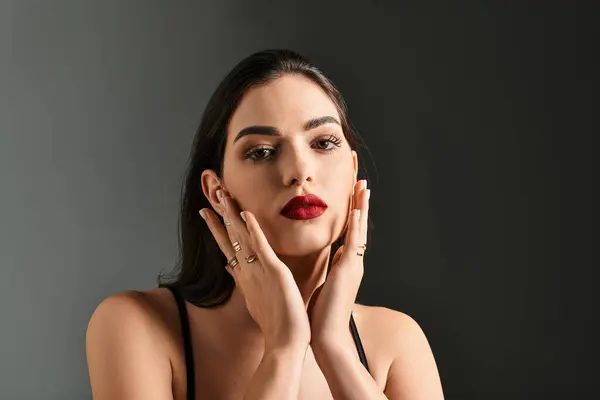 A graceful young woman showcases her elegance with brown hair and bold red lips, exuding confidence. — Stock Photo