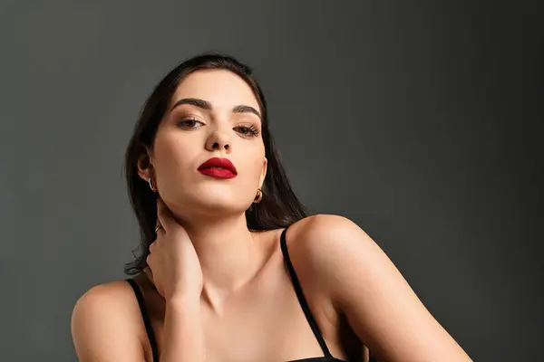 A stunning young woman poses confidently against a soft grey backdrop, showcasing her beauty. — Stock Photo