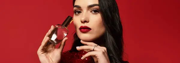 Young woman with red lips poses in a studio, exuding beauty and confidence while holding perfume, banner — Stock Photo