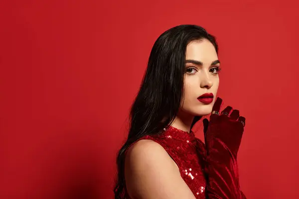 A confident young woman with bold red lips and gloves showcases her beauty against a vivid backdrop. — Stock Photo