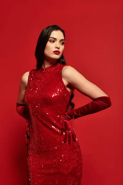 Uma bela jovem mulher com cabelo castanho mostra seu estilo confiante em um vestido de lantejoulas vermelhas. — Fotografia de Stock