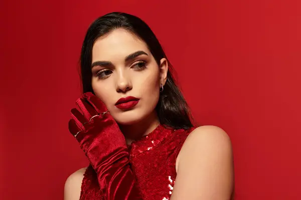 A young woman with glamorous makeup poses gracefully in a bright studio with red backdrops. — Stock Photo