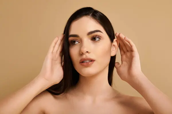 Jeune femme met en valeur la peau rayonnante et l'allure dans un studio, mettant en valeur la beauté et le bien-être. — Photo de stock