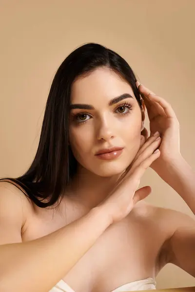 A young woman with radiant skin poses thoughtfully, highlighting her beauty in a soft-lit studio. — Stock Photo