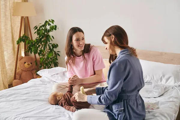 Two joyful mothers lovingly care for their child in a warm, inviting home. — Stock Photo