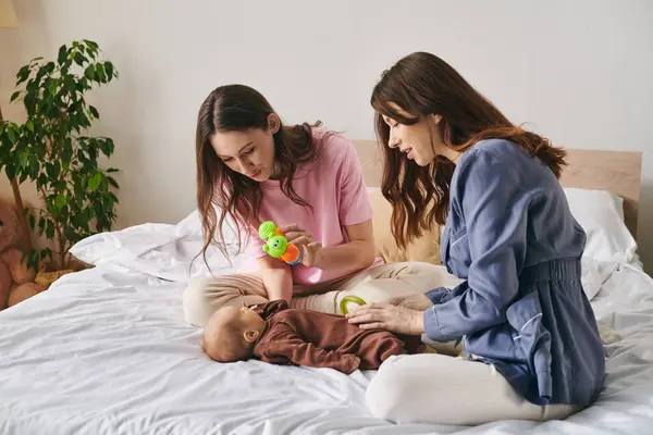 Two loving mothers share a joyful moment with their baby, enjoying playful interactions at home. — Stock Photo