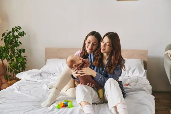 Zwei liebevolle Mütter teilen einen zärtlichen Moment mit ihrem Kind an einem warmen Muttertag zu Hause. — Stockfoto